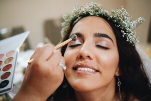 Smiling Bride getting her makeup done on wedding day wearing a flower crown