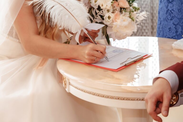 Bride hand with a pen signing wedding license.